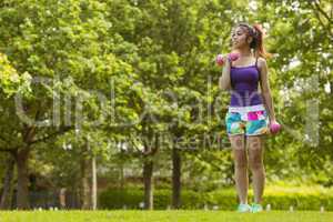 Healthy woman lifting dumbbells in park
