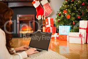 Redhead woman lying on floor using laptop at christmas