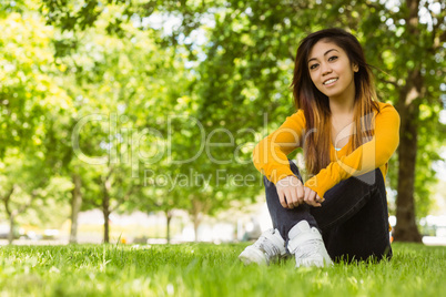 Beautiful relaxed woman sitting on grass at park