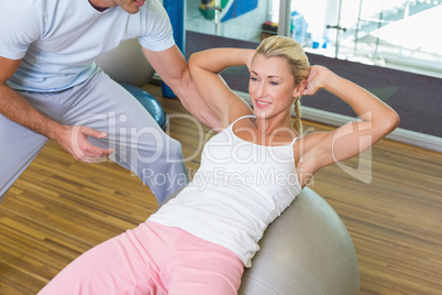 Trainer assisting woman with abdominal crunches