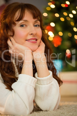 Smiling woman is resting her head on her hands