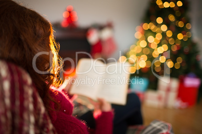 Rear view of redhead reading at christmas