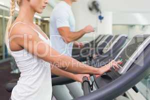 Side view mid section of couple running on treadmills at gym
