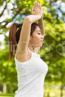 Healthy woman with joined hands over head at park