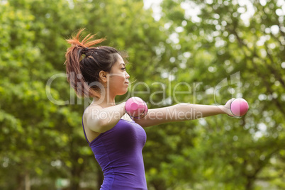 Healthy woman lifting dumbbells in park