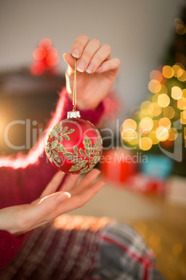 Woman in jumper holding red bauble at christmas