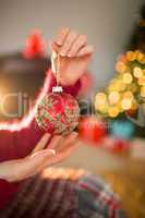 Woman in jumper holding red bauble at christmas