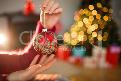 Woman in jumper holding red bauble