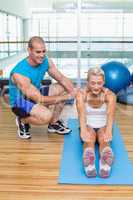 Trainer assisting woman with exercises at fitness studio