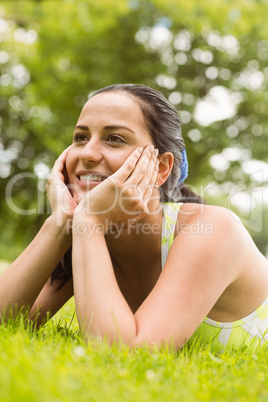 Thoughtful fit brunette lying on the grass