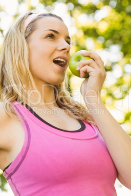 Fit blonde eating green apple