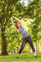 Pretty athletic redhead stretching in park