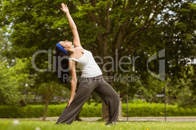 Peaceful brunette doing yoga in the park