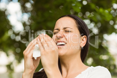 Sick brunette holding tissue sneezing