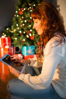 Redhead woman sitting on floor using tablet at christmas