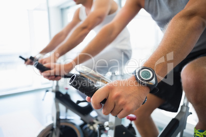 Mid section of men working on exercise bikes at gym