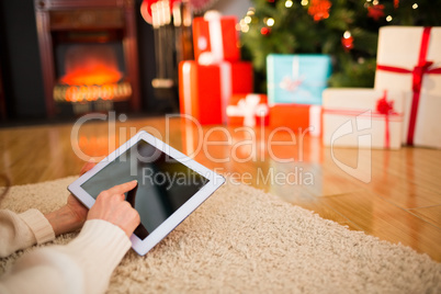 Redhead woman lying on floor using tablet at christmas