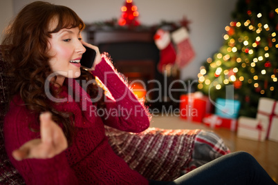 Smiling redhead phoning and gesturing at christmas