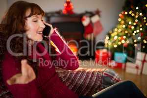 Smiling redhead phoning and gesturing at christmas