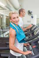 Fit young couple running on treadmills at gym
