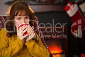 Smiling redhead drinking hot drink at christmas