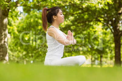 Healthy woman sitting with joined hands at park