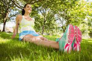 Happy brunette in sportswear relaxing on the grass