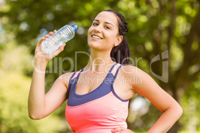 Fit smiling brunette holding her water bottle