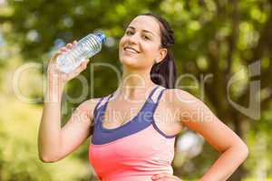 Fit smiling brunette holding her water bottle