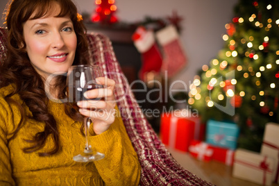 Woman sitting on a couch while holding a glass of red wine