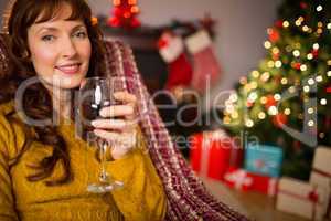 Woman sitting on a couch while holding a glass of red wine