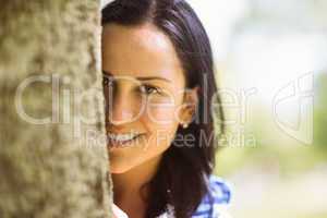 Portrait of a pretty brunette leaning against a tree