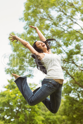 Excited brunette jumping in the park