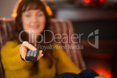 Smiling redhead holding remote control at christmas
