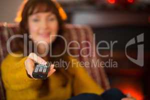 Smiling redhead holding remote control at christmas