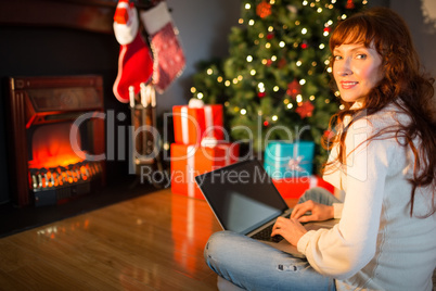 Redhead woman sitting on floor using laptop at christmas Redhead woman sitting on floor using laptop at christmas