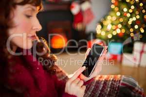 Cheerful redhead using smartphone at christmas