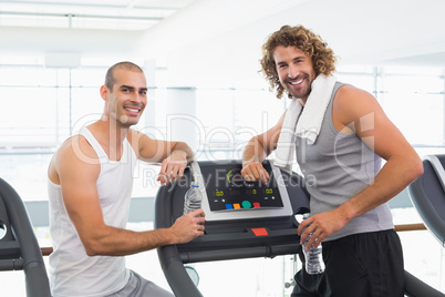 Smiling male trainer and fit man at gym