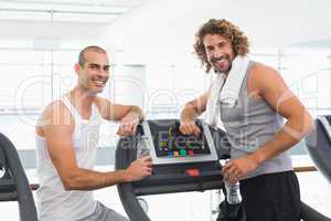 Smiling male trainer and fit man at gym