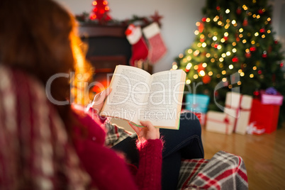 Rear view of redhead reading at christmas