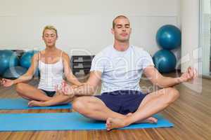 Couple sitting in lotus posture at fitness studio