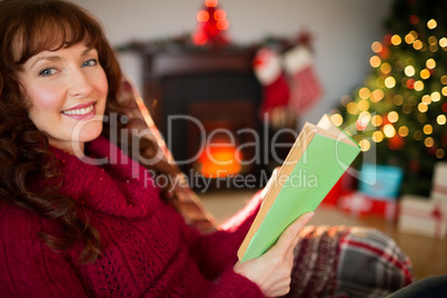 Smiling red hair reading on the couch at christmas