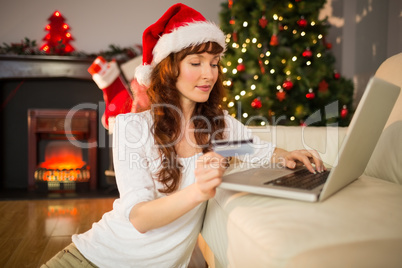 Red hair in santa hat shopping online with laptop