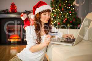 Red hair in santa hat shopping online with laptop