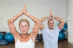 Couple with joined hands and eyes closed at fitness studio
