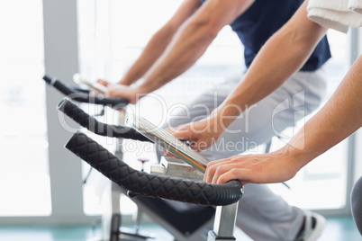 Mid section of couple working on exercise bikes at gym