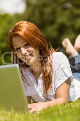 Pretty redhead happy and lying with her laptop