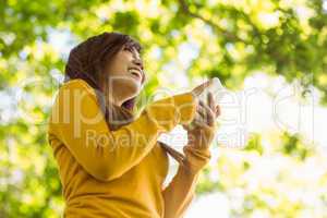 Beautiful young woman text messaging in park