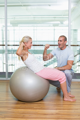 Male trainer assisting woman with abdominal crunches at gym