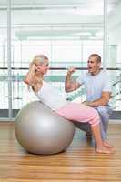 Male trainer assisting woman with abdominal crunches at gym